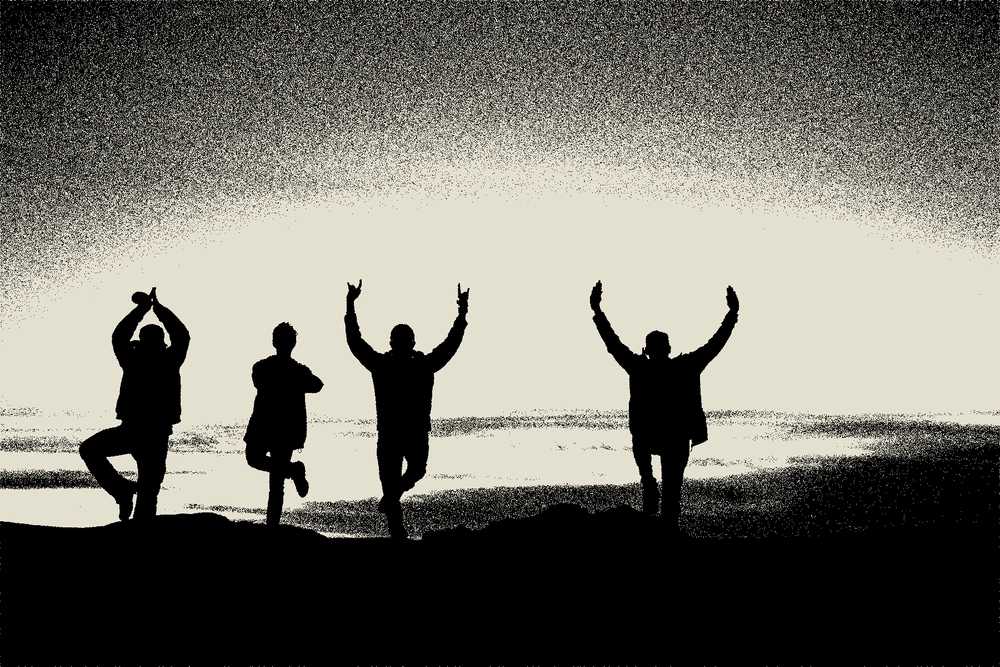 Silhouette of four people walking in a row, cheering with their hands up.