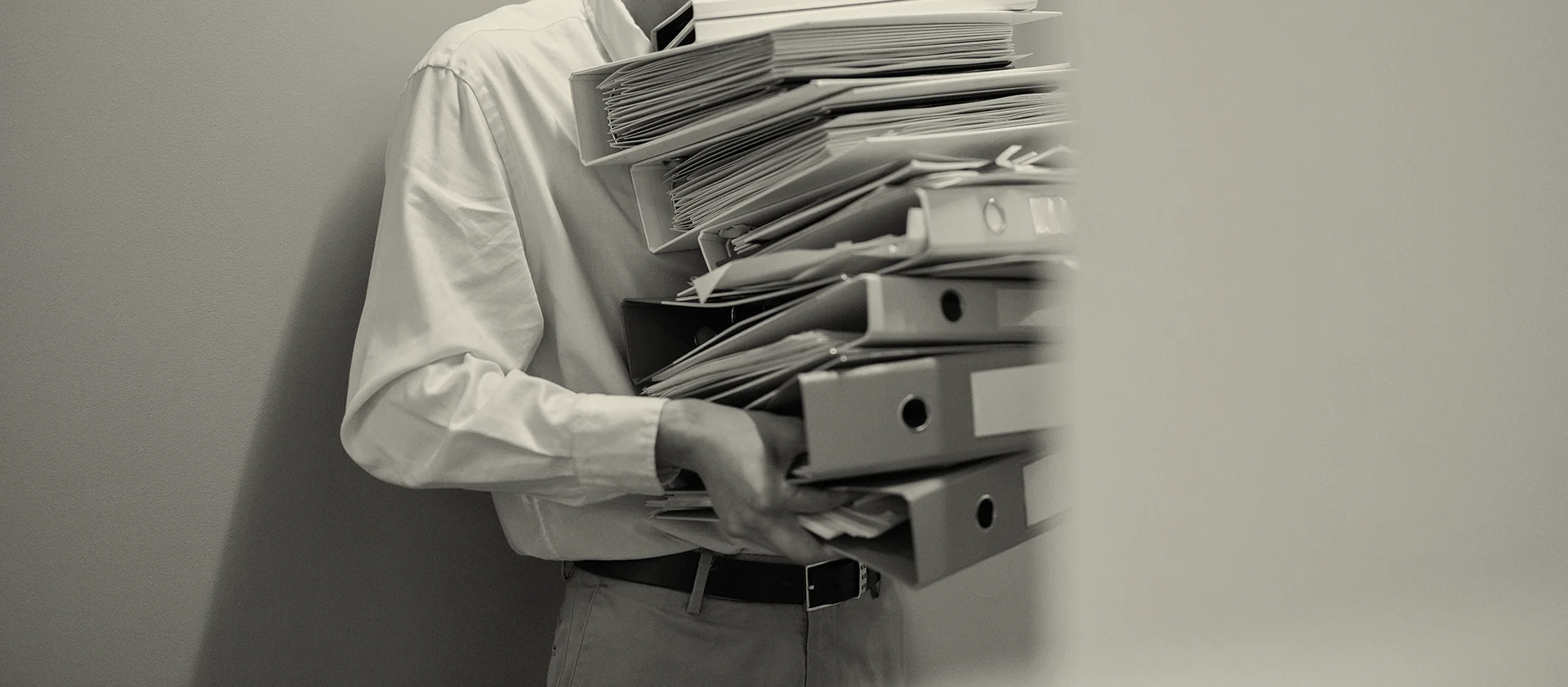 a man with glasses holding books and folders